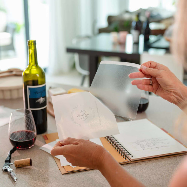 Person peeling away the backing paper from the wine bottle label remover to adhere to wine label