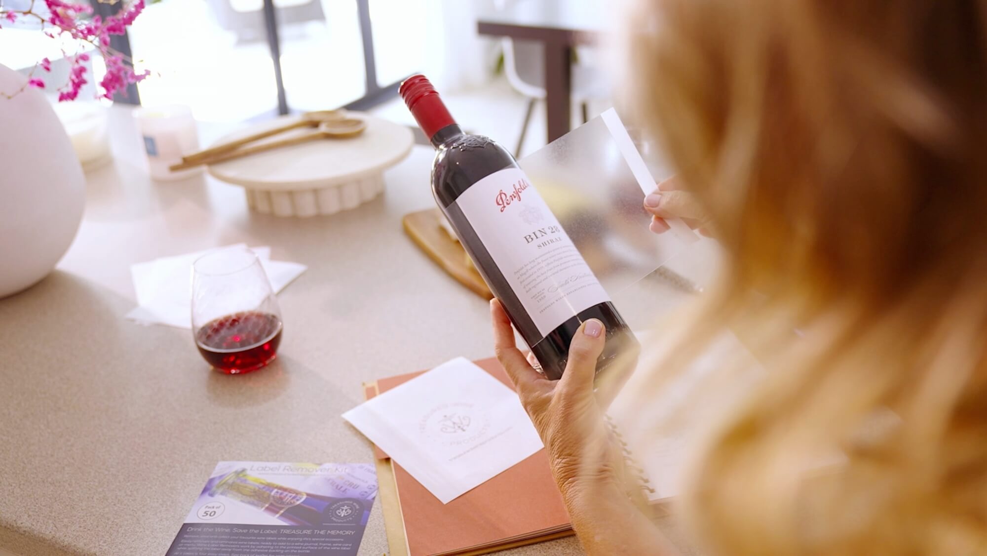 person adhering wine label remover over wine label preparing to remove and save the label